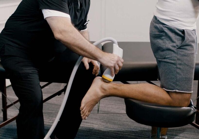 doctor applying softwave therapy to patients achilles tendon