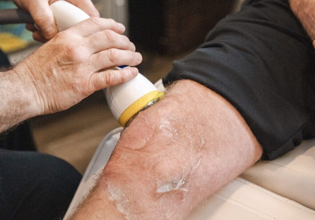 doctor applying softwave therapy to patients knee