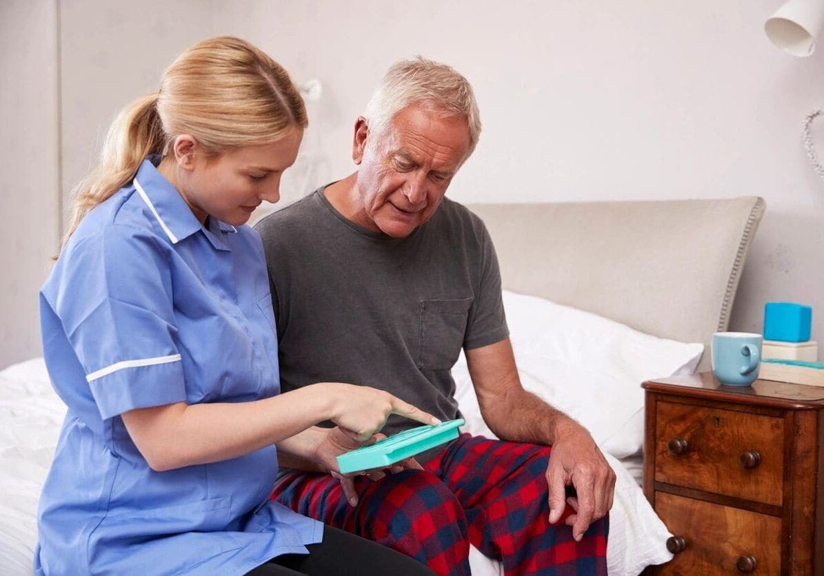 A nurse is helping an older man with his medical equipment.
