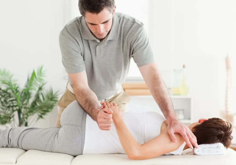 A man is stretching the woman 's arm.