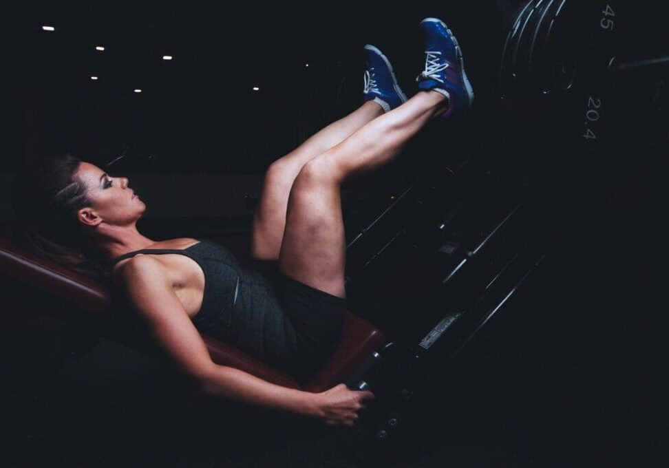 woman in the gym doing a leg press correctly to avoid injury